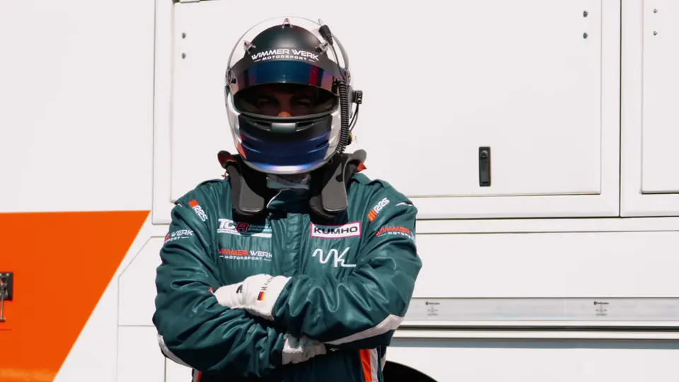 Maximilian Kochendörfer im Rennanzug mit verschränkten Armen vor dem Teamtruck